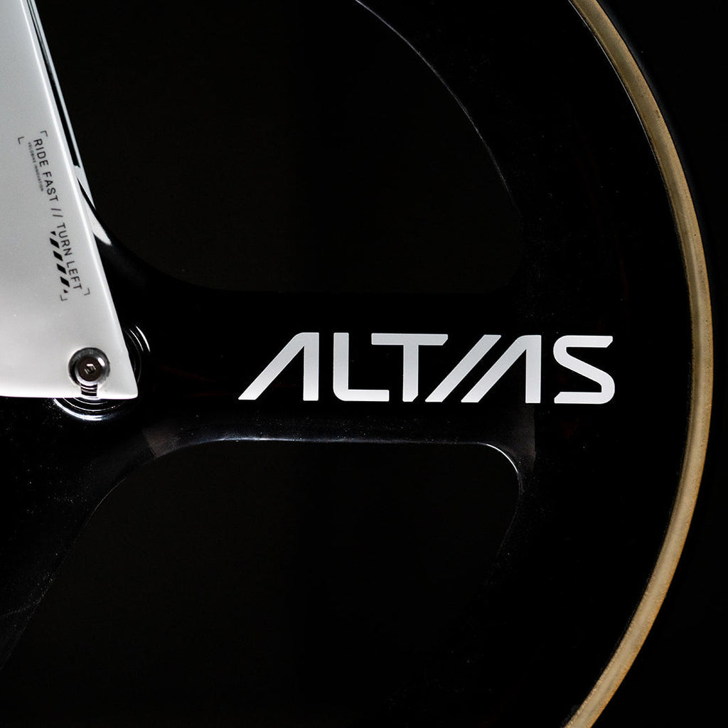 Close-up of a black bicycle wheel with a silver aluminum fork and the white ALTIAS brand logo on the frame, set against a dark background.